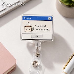 May include: A rectangular badge reel featuring a pixel art computer error window graphic. The blue header reads Error with an X icon. The white body displays a sad coffee mug icon with steam and the text You need more coffee. below an OK button.