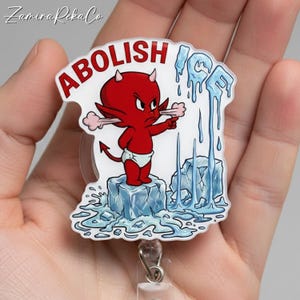 May include: A red devil cartoon character with the word "ABOLISH" above it, pointing at melting ice. The word "ICE" is also featured. The badge is on a clear background with a retractable reel.