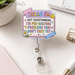 May include: A clear acrylic badge reel featuring a rectangular design with a scalloped border. The text reads: HELLO I'M NOT OVERTHINKING I'M PRE-SOLVING PROBLEMS THAT DON'T EXIST YET. It includes colorful accents like a smiley face, stars, and a daisy.