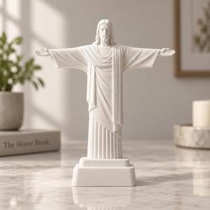 Könnte beinhalten: Eine weiße, matte Statue von Jesus Christus, die mit ausgebreiteten Armen in einer weiten Pose steht. Die Figur trägt ein langes, drapiertes Gewand mit vertikalen Falten am Saum und steht auf einem rechteckigen Sockel. Die Oberfläche ist glatt.