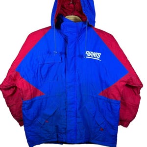May include: A blue and red hooded jacket with the word "GIANTS" in white on the chest. The jacket has a blue body with red sleeves and shoulder panels. It features a front zipper and two front pockets.
