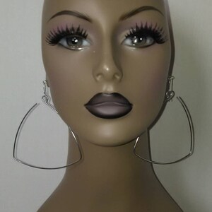 May include: A mannequin wearing silver triangle-shaped hoop earrings.