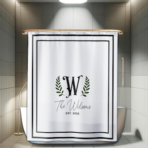 May include: A white shower curtain featuring a double black rectangular border. The center displays a large black letter W flanked by two green laurel branches, with the text The Wilsons and EST. 2025 printed in black below the letter.