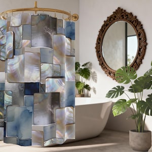 Op de afbeelding: Een douchegordijn met een mozaïekontwerp in tinten blauw, grijs en iriserend parelmoer. Het gordijn hangt aan een goudkleurige gebogen stang. Een decoratieve spiegel en potplanten zijn ook zichtbaar.