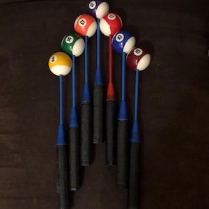 May include: A set of nine pool cue sticks with numbered balls on top. The balls are red, blue, green, yellow, and white. The sticks are black with blue tips.
