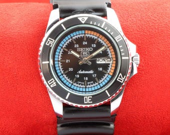 vintage Montre-bracelet automatique japonaise Seiko 5, date du jour, cadran de course noir, lunette tournante, 40 mm.