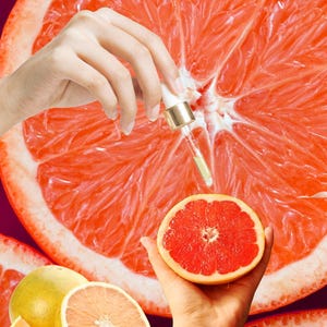 May include: A vibrant image showcasing a halved grapefruit with a hand holding a dropper dispensing a clear liquid. Additional grapefruit slices and a whole grapefruit are also visible, suggesting a skincare or wellness theme.