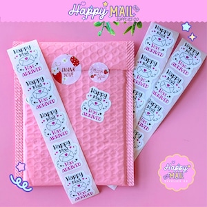 May include: Pink padded envelope with sticker rolls and individual stickers. The stickers feature a heart and envelope design with the text "Happy Mail" and "Has Arrived". Also included are "Thank You" stickers.