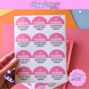 May include: A sheet of pink and white warning stickers. Each sticker is a half-circle with the word "WARNING" and the text "Opening this package will cause extreme happiness". These stickers are for packaging supplies.