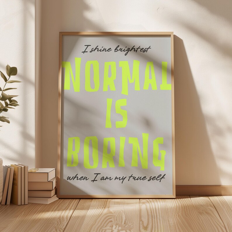 May include: A framed poster with the words "NORMAL IS BORING" in bright neon green, set against a light gray background. The text "I shine brightest" and "when I am my true self" are also included. The frame is a light wood color.