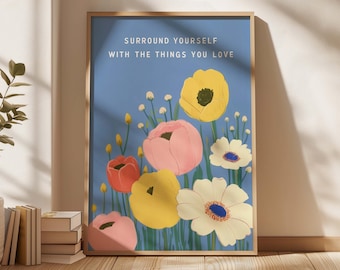 May include: A framed art print featuring colorful flowers against a blue background. The artwork includes yellow, pink, red, and white flowers with the text "SURROUND YOURSELF WITH THE THINGS YOU LOVE" in white lettering.