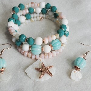 May include: A multi-strand bracelet with white, pink and teal beads, accented with a seashell charm and a starfish. Matching earrings with teal beads and seashell charms.