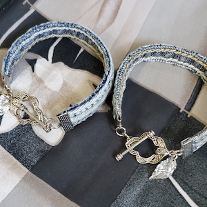 May include: Two denim bracelets with silver metal clasps and leaf accents. The bracelets are made from repurposed denim fabric.