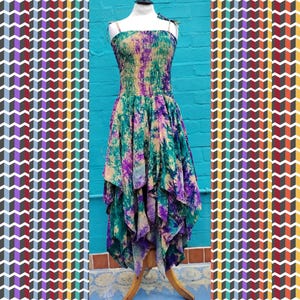May include: A vibrant, strapless dress with a tie-dye design in green, purple, and yellow. The dress features a fitted bodice and a flowing, asymmetrical skirt. The dress is displayed on a mannequin.