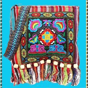 May include: A colorful, embroidered shoulder bag with a black background and vibrant floral designs in red, yellow, blue, and green. The bag has a patterned strap and a fringe with tassels. The bag is approximately 12 inches wide and 10 inches tall.