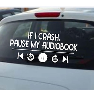 Puede incluir: Adhesivo de vinilo blanco para coche con el texto "IF I CRASH, PAUSE MY AUDIOBOOK" e iconos de control del reproductor multimedia. El adhesivo está en la luneta trasera de un coche blanco.