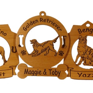 K&ouml;nnte beinhalten: Drei Holzornamente mit lasergravierten Bildern eines Pferdes, eines Golden Retrievers und einer Bengal-Katze. Die Ornamente sind mit den Namen "Spirit", "Maggie & Toby" und "Yazzy" verziert.
