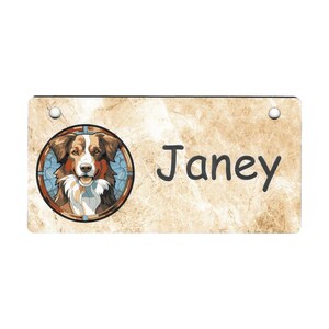 May include: A tan and brown dog with white fur is featured in a stained glass style illustration on a rectangular sign with the name "Janey" written in black.