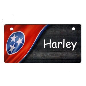 May include: A wooden sign with a red, white, and blue Tennessee flag design. The sign has two holes for hanging and the name "Harley" is written in white on the sign.