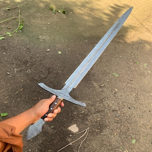 May include: A long, silver sword with a wooden handle. The blade has a detailed pattern and the handle has a dark wood finish.