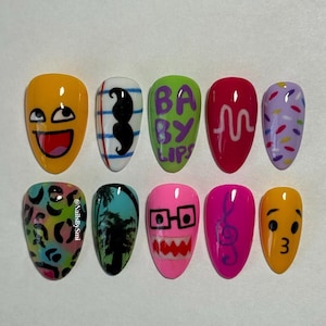 Könnte beinhalten: Ein Set aus zehn künstlichen Nägeln mit verschiedenen Designs. Die Designs umfassen Emojis, einen Schnurrbart, den Text "BABY LIPS", eine Wellenlinie, Streusel, Leopardenmuster, eine Palme, ein Cartoon-Gesicht, eine Musiknote und die Zahl 3.
