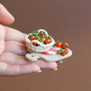 May include: A miniature wooden cutting board with a small crocheted basket filled with red and yellow tomatoes. A few extra tomatoes are scattered on the board.