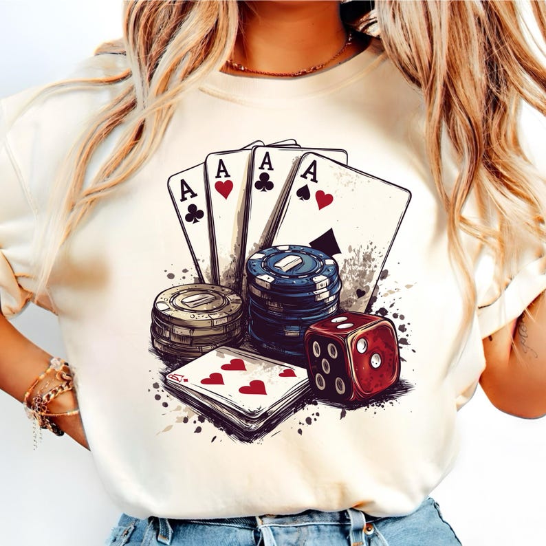 Puede incluir: Una camiseta blanca con un dise&ntilde;o gr&aacute;fico de cartas de juego, fichas de p&oacute;quer y un dado rojo. Las cartas son ases de tr&eacute;boles, corazones y picas. El dise&ntilde;o es de estilo vintage con un efecto acuarela.