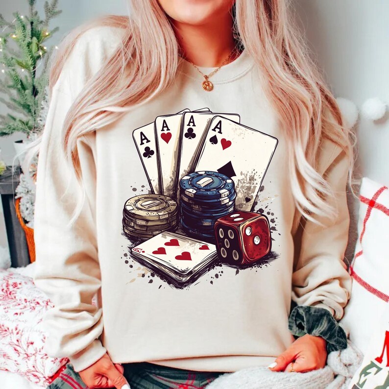 Puede incluir: Una sudadera blanca con un estampado gr&aacute;fico de cuatro ases, fichas de p&oacute;quer y un dado rojo. El gr&aacute;fico est&aacute; en un estilo vintage con un fondo descolorido.