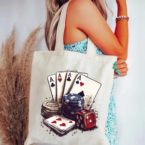 Puede incluir: Una bolsa de lona blanca con un dise&ntilde;o de cuatro ases de cartas de juego, fichas de p&oacute;quer y un dado rojo. El dise&ntilde;o es de estilo vintage con un efecto grunge.