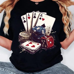 Puede incluir: Camiseta negra con un dise&ntilde;o gr&aacute;fico de cuatro ases, fichas de p&oacute;ker y un dado rojo. El dise&ntilde;o es de estilo vintage con un fondo grunge.