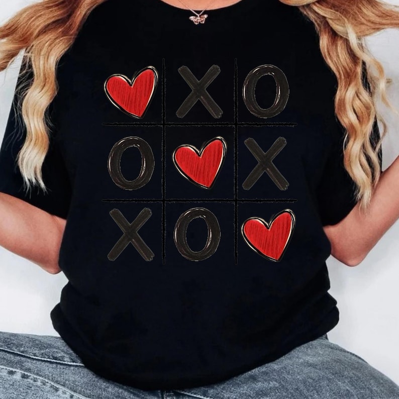 May include: Black t-shirt with a red heart and X's and O's in a tic-tac-toe board design.