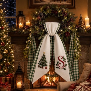Peut inclure: Un chemin de cheminée décoratif en tissu avec une bordure à carreaux vichy verts et blancs, un sapin de Noël brodé avec des cadeaux et une lettre S rouge brodée entourée de feuilles de houx, drapé sur une cheminée en pierre.