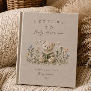 Könnte beinhalten: Ein beiges Hardcover-Buch mit dem Titel Letters to Baby Harrison, das einen gestickten Teddybären zeigt, der inmitten von Wildblumen ein Buch liest. Der Einband enthält den Text Jason & Kendall's Baby Shower 2026 in Serif- und Schreibschrift.