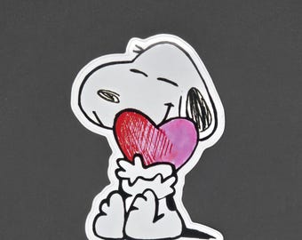 May include: A white cartoon dog with black eyes and a black nose is holding a red and pink heart in its arms. The dog is sitting on a gray background.
