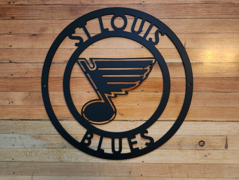 May include: Black metal sign with the words "St. Louis Blues" in a circle. The Blues logo is a stylized note with a wing.