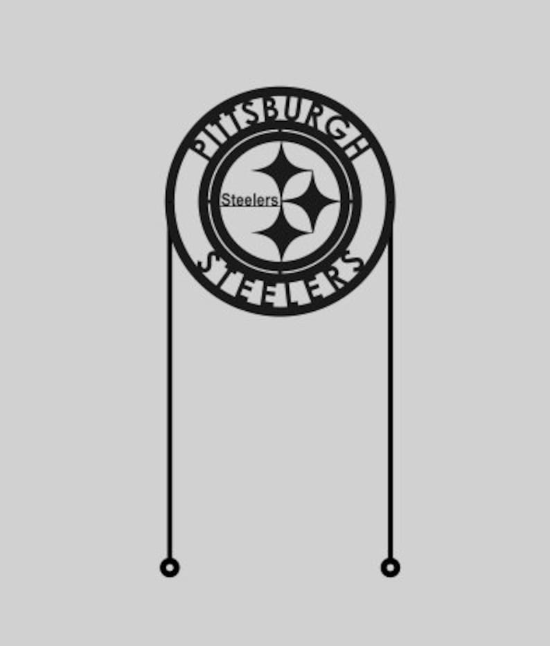 May include: Black metal Pittsburgh Steelers sign with the team logo and the words "Pittsburgh Steelers" in a circular design. The sign has two vertical lines extending downwards with small circles at the ends.
