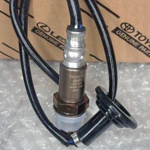 May include: A metallic oxygen sensor with a black wire harness and a black rubber grommet. The sensor body is engraved with the text TOYOTA 89465-02190 DENSO 1780 03R14. It features a silver upper section, a bronze-coloured hexagonal base, and a clear plastic cap.