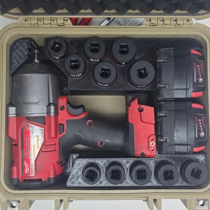 May include: A tan hard-shell carrying case containing a red and black cordless impact wrench, two rectangular lithium-ion batteries, and a black custom-fitted organiser tray holding multiple black metal impact sockets of varying sizes.
