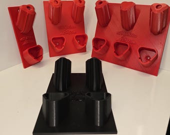 May include: Red and black climbing holds in various shapes and sizes. The red holds are mounted on red rectangular boards. The black holds are mounted on a black square board. The text "MOUNTAIN3D" is visible on the red boards.