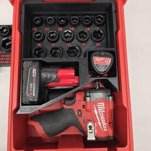 May include: A red plastic tool case with a clear lid, containing a black insert with sockets, a red and black impact wrench, and a battery. The case has the Milwaukee brand name.
