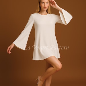 Puede incluir: Minivestido color crema con mangas largas y pu&ntilde;os acampanados. El vestido tiene un cuello redondo y una falda acampanada. El texto "La Verart Pattern" est&aacute; impreso en la parte delantera del vestido.