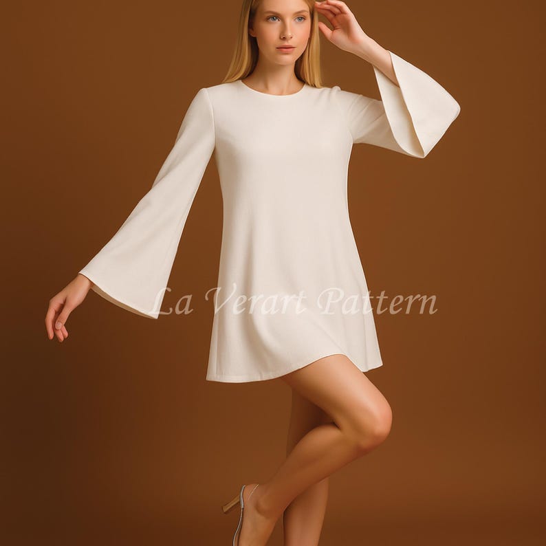 Puede incluir: Minivestido color crema con mangas largas y pu&ntilde;os acampanados. El vestido tiene un cuello redondo y una falda acampanada. El texto "La Verart Pattern" est&aacute; impreso en la parte delantera del vestido.