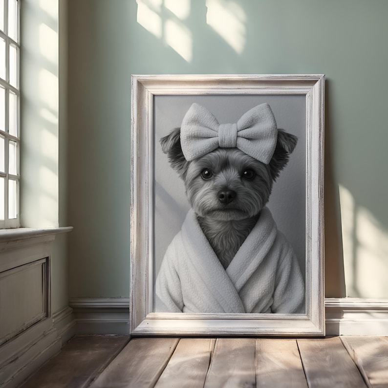 Peut inclure: Portrait encadr&eacute; en noir et blanc d'un petit chien portant un n&oelig;ud blanc et un peignoir blanc. Le chien a des poils fonc&eacute;s et regarde directement le spectateur. Le cadre est blanc et le fond est vert clair.