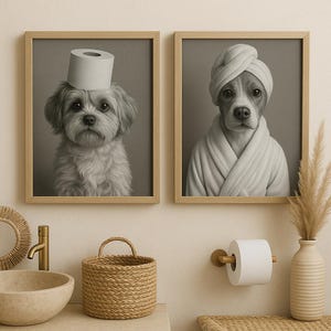 May include: Two framed grayscale prints of dogs. One dog wears a toilet paper roll as a hat, the other wears a towel turban and a robe. The bathroom setting includes a woven basket, a sink, and a toilet paper holder.