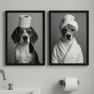 May include: Two framed black and white prints. One shows a beagle with a toilet paper roll on its head. The other print features a beagle wearing a white robe and a towel on its head. The prints are displayed on a gray wall.