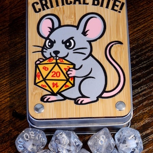 May include: A wooden box with the text "CRITICAL BITE!" and a cartoon mouse holding a yellow and red twenty-sided die. Several clear, multi-sided dice are scattered below the box, suggesting a tabletop gaming theme.