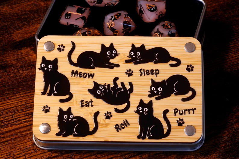 以下が含まれることがあります： 黒い猫のデザインが施された木製の箱。箱には蓋があり、開けると黒い猫が描かれたサイコロのセットが現れます。サイコロは黒、白、金など様々な色をしています。箱には「Meow」、「Eat」、「Sleep」、「Purrr」、「Roll」の文字が印刷されています。