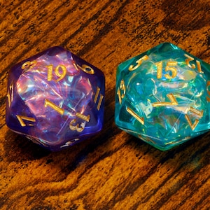 May include: Two iridescent dice with gold numbers. The dice are blue and purple and have a swirling pattern.