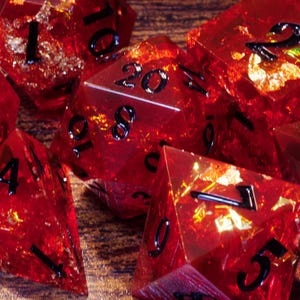 Può includere: Un set di dadi rossi, trasparenti e dorati con numeri neri. I dadi sono realizzati in resina e hanno una finitura scintillante e brillante.
