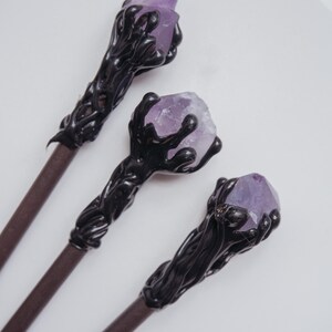 Puede incluir: Tres varitas negras con puntas de cristal de amatista. Las varitas tienen un dise&ntilde;o detallado e intrincado que se asemeja a una mano sosteniendo el cristal.